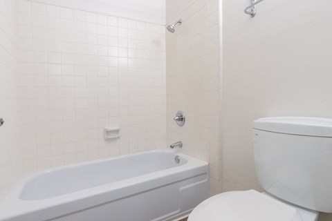 A white bathroom with a tub and toilet.