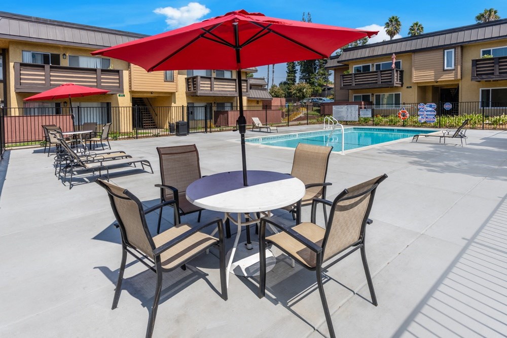 our apartments have a patio with a table and chairs and a pool