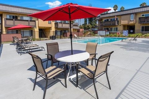 our apartments have a patio with a table and chairs and a pool