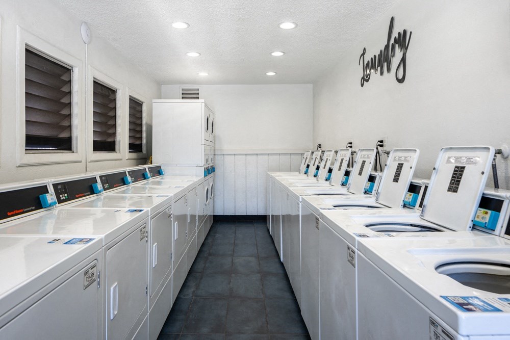 a laundry room filled with lots of white washing machines