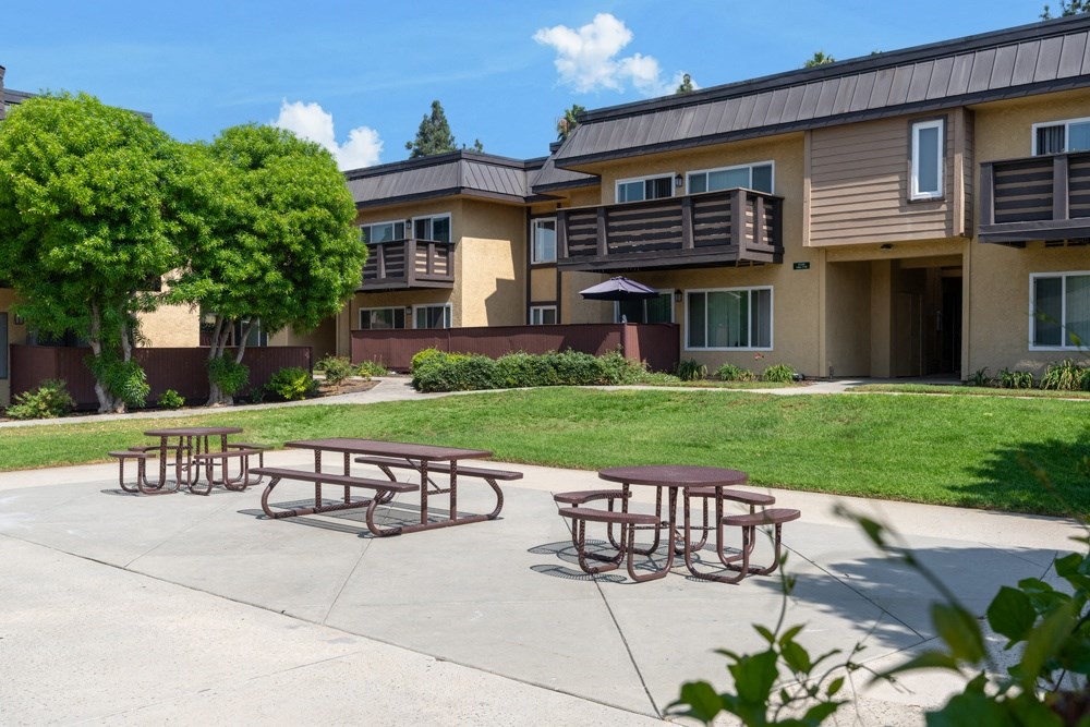 Picnic tables are set up in front of apartment buildings.
