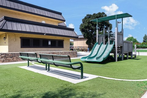 a playground with a slide and a bench in front of a building