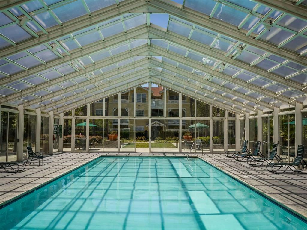 an indoor swimming pool with chairs and umbrellas