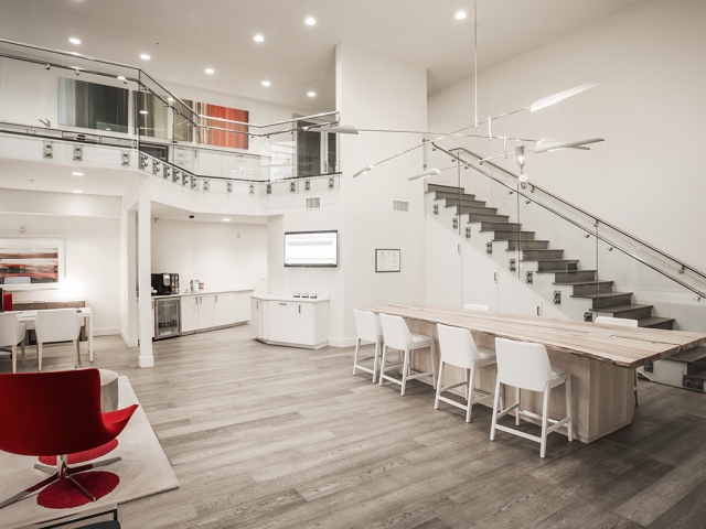 A modern kitchen with a red chair and a wooden table.