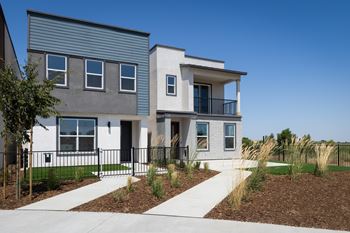 A modern two-story house with a white and grey exterior and a black fence.