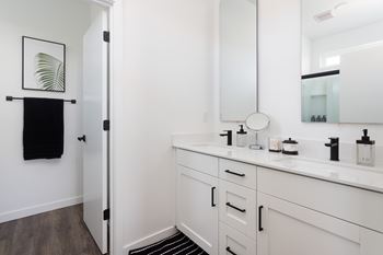 A bathroom with a white vanity and a mirror.