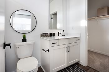 A white bathroom with a toilet, sink, and mirror.