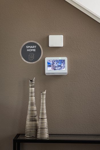 A wall with a Smart Home device and a picture of a snowy scene.