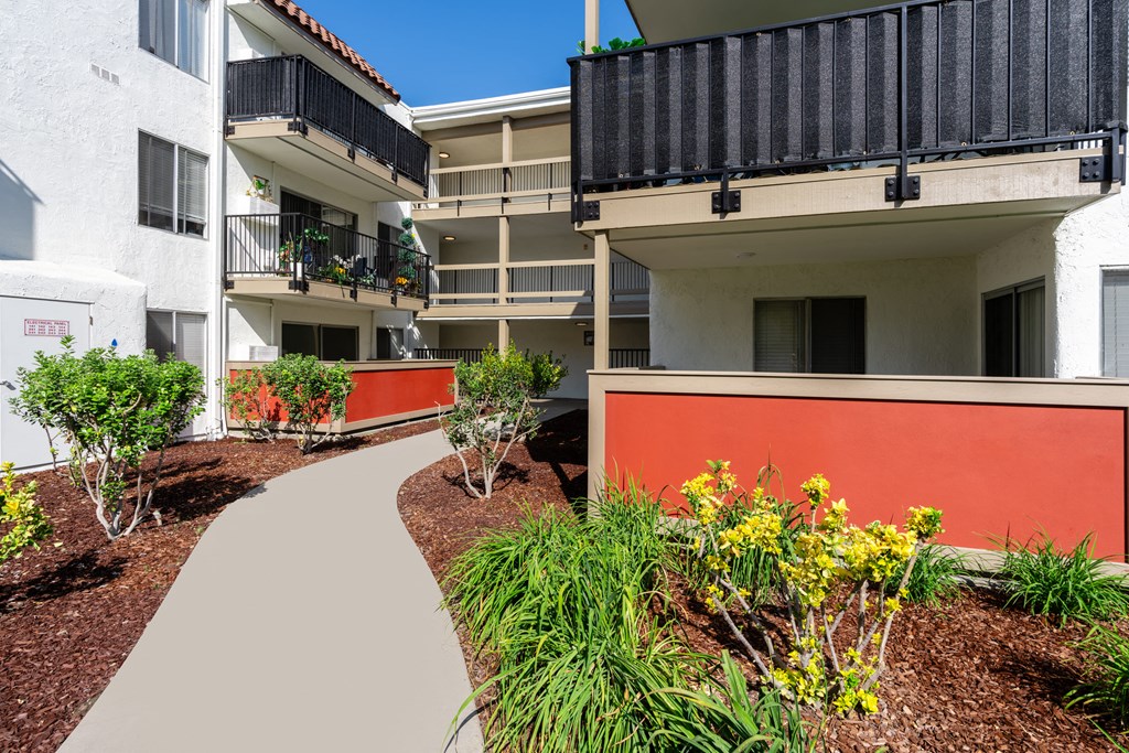an exterior view of an apartment building with a walkway and plants
