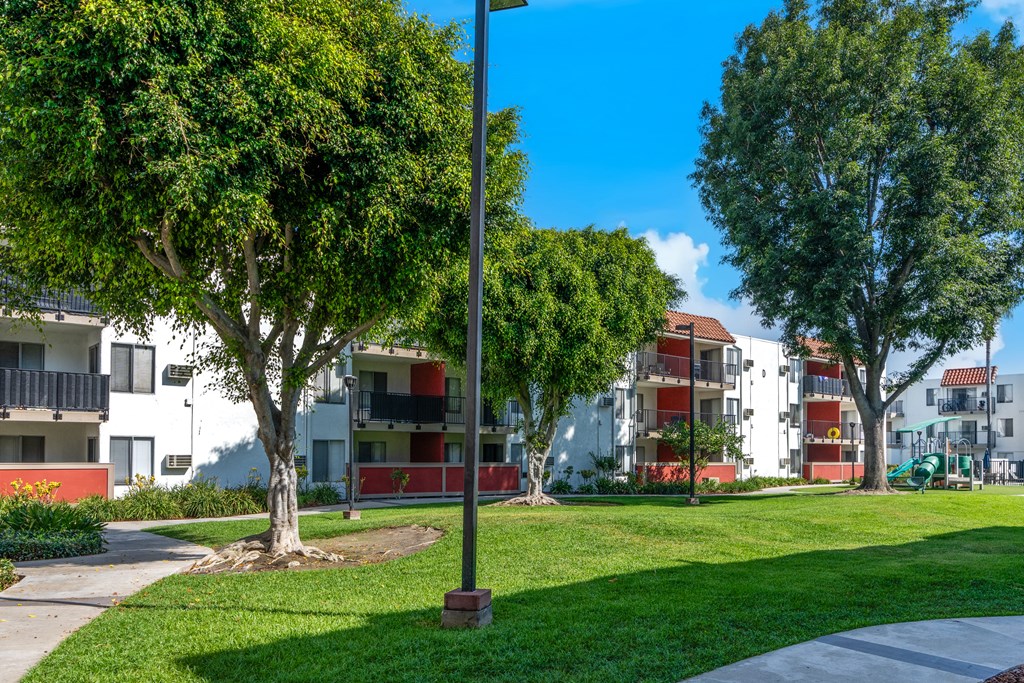 a park with trees in front of an apartment building