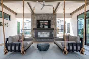 Outdoor lounge area with a fireplace and two hanging sofas.