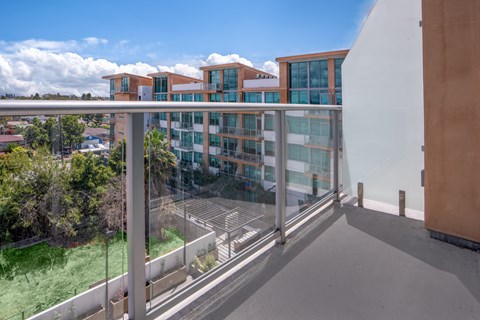 A modern building with a glass balcony overlooking a parking lot.