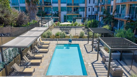 A large outdoor swimming pool surrounded by sun loungers and umbrellas.