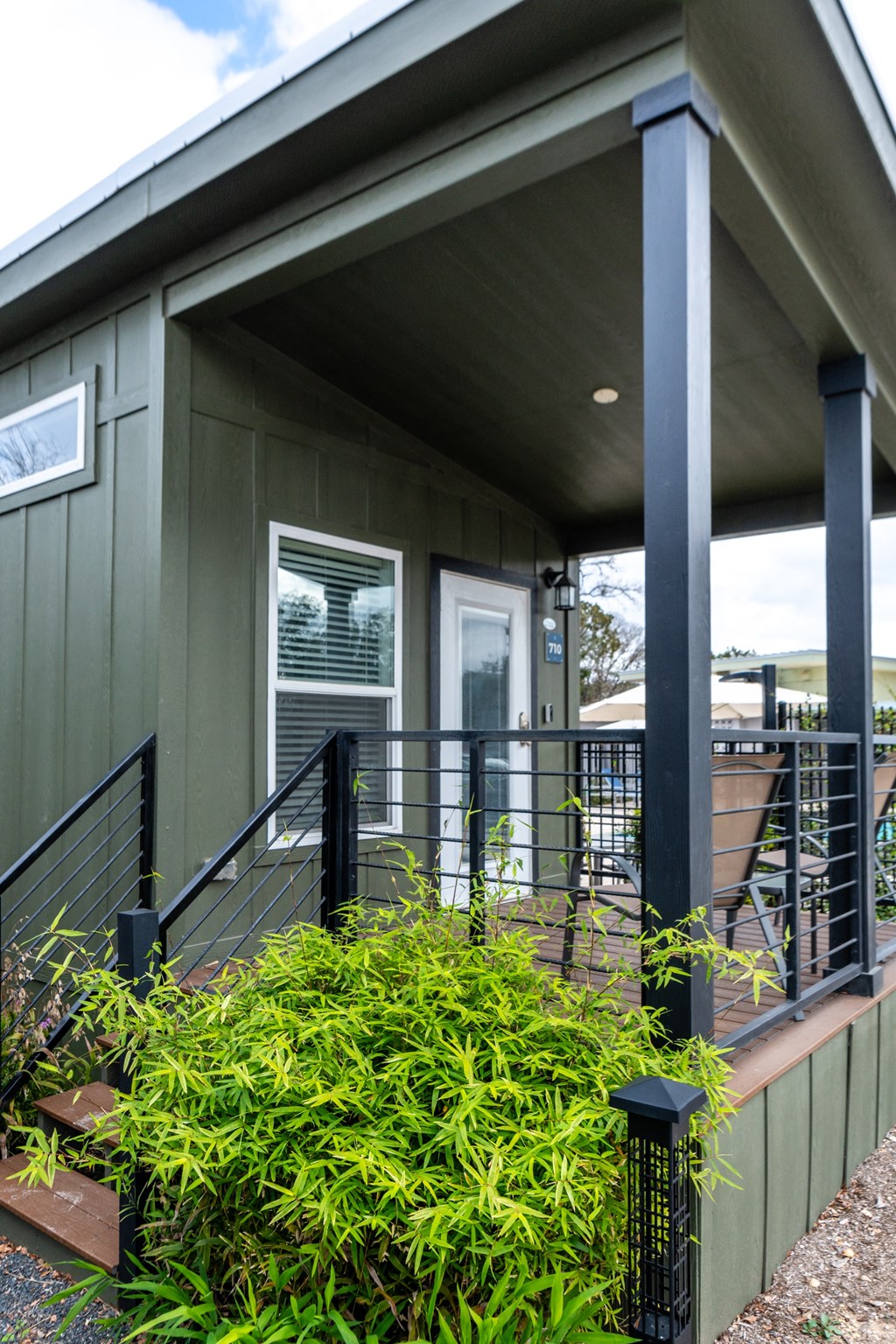 the front of a green house with black railings and a porch