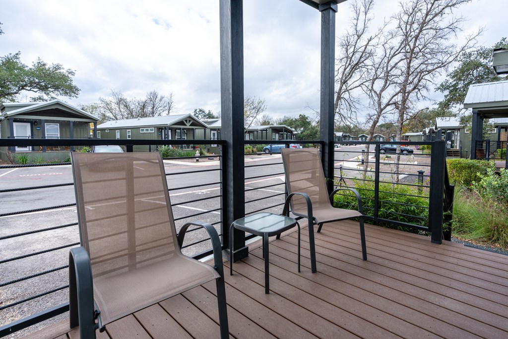 two chairs on a deck with a fence and a house in the background