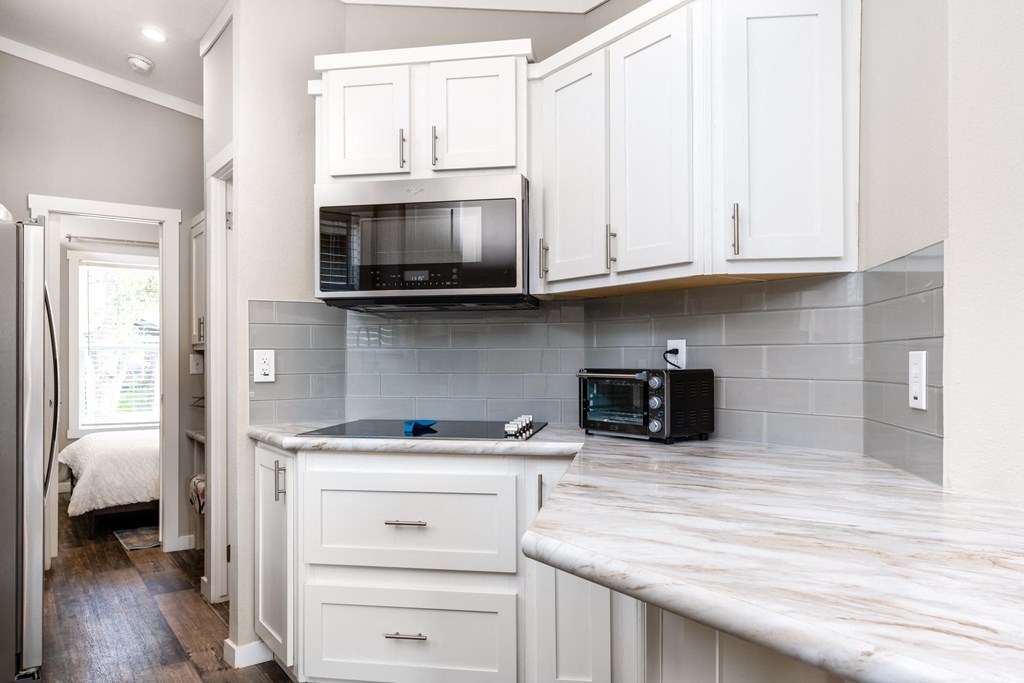 a small kitchen with white cabinets and a microwave