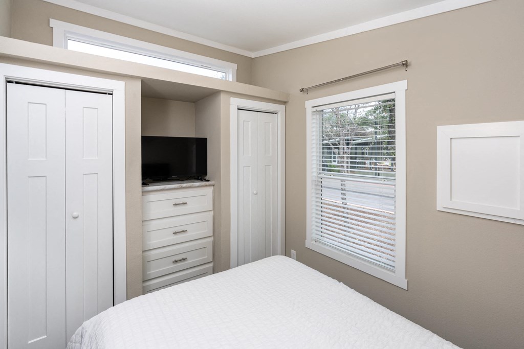 a small bedroom with a bed and a window and a tv