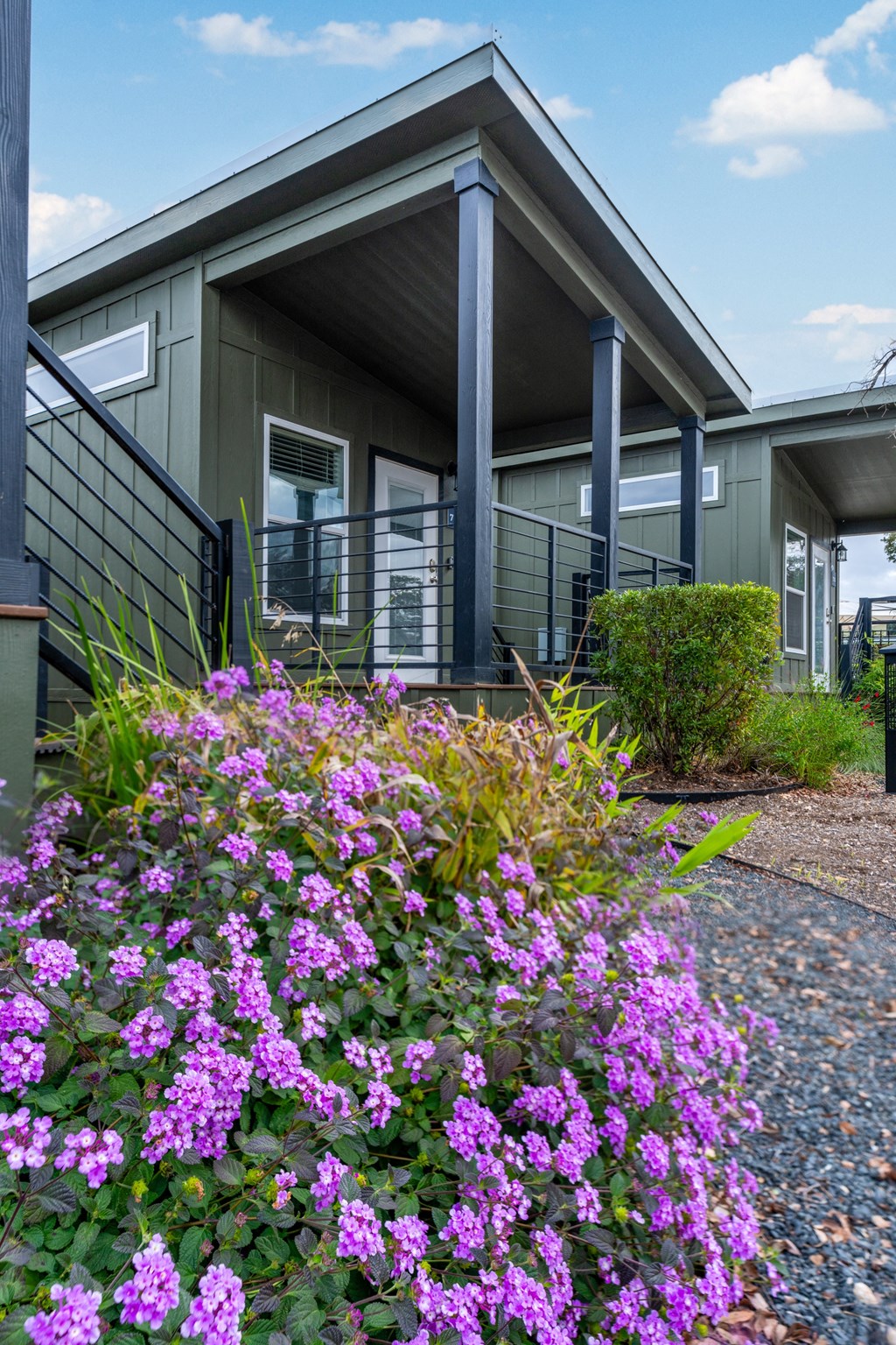 the front of a house with purple flowers in front of it