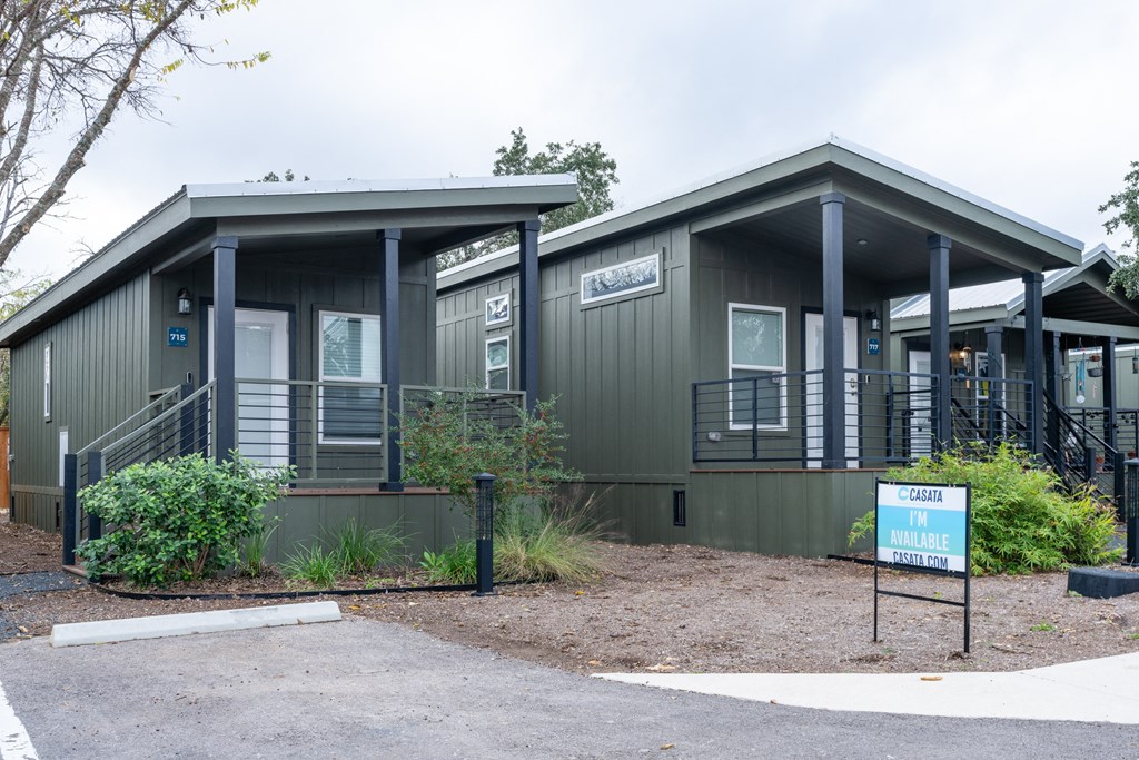 a green building with a porch and a sign in front of it