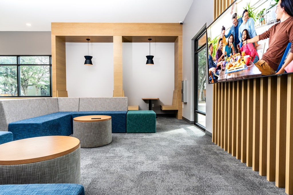 a lobby with blue couches and tables and a tv on the wall