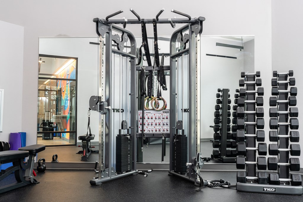 a fitness room with cardio equipment and weights on the floor