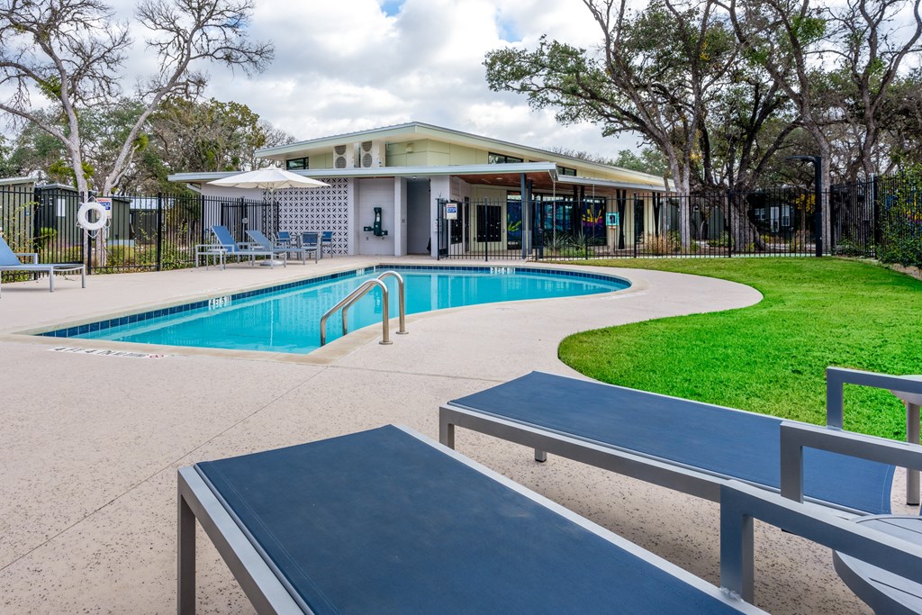 a swimming pool with benches and a building in the background