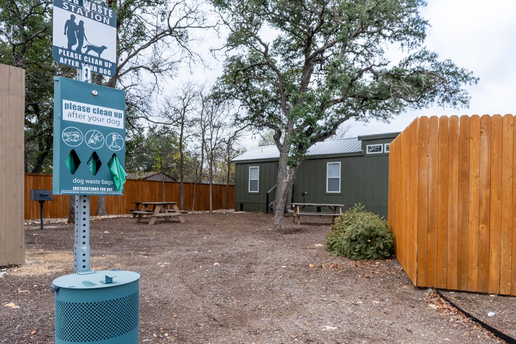 a park with a wooden fence and a sign for a dog park
