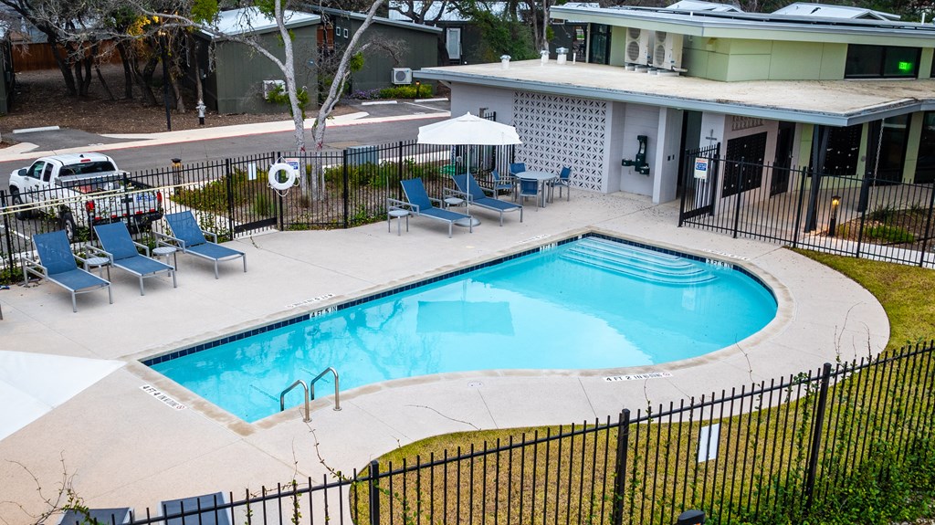 a swimming pool in front of a hotel with chairs and a building
