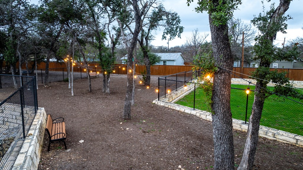 South Austin Apartments - Casata Austin - Gated Dog Park With Benches, String Lighting, And Trees