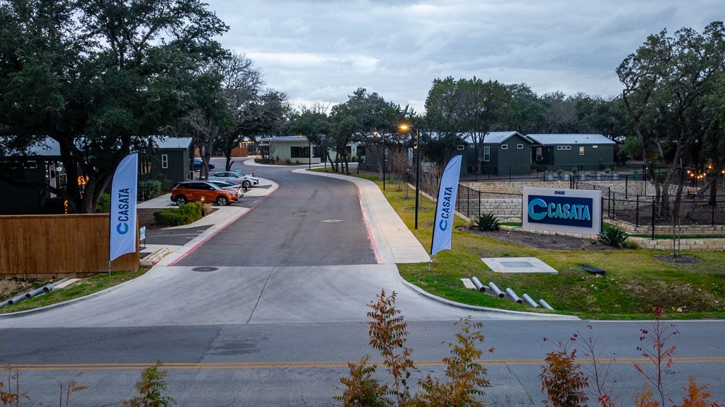 a road leading to a sign for cbh and a building with cars parked in
