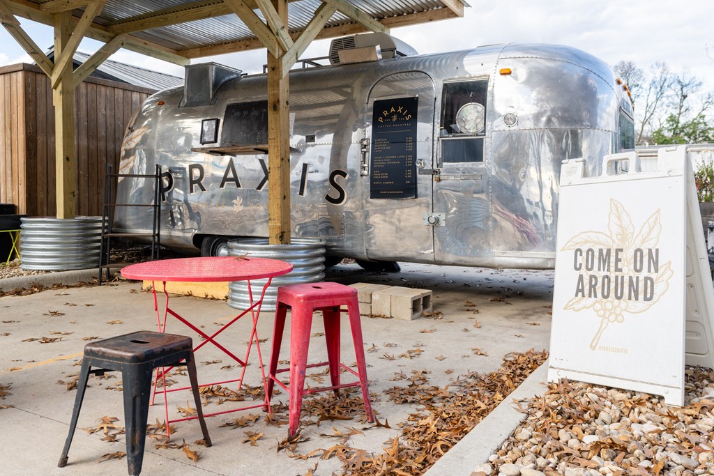 a trailer with a sign that reads come on around and a red table and chairs