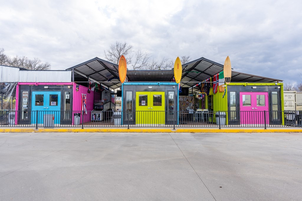 the front of a building with colorful doors and a parking lot