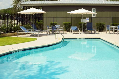 Two-Bedroom Apartments in South Austin, TX - Casata Austin - Resort-Style Swimming Pool with Lounge Seats, Tables and Chairs, and Umbrellas.
