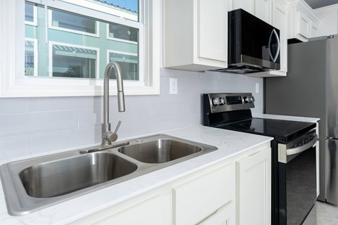 A modern kitchen with a double sink and stainless steel appliances.