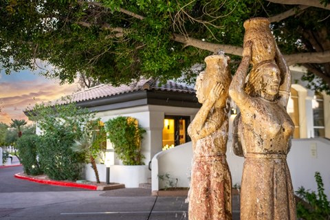 A statue of a woman holding a child stands in front of a building.
