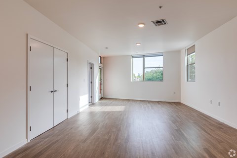 A large empty room with wooden floors and white walls.