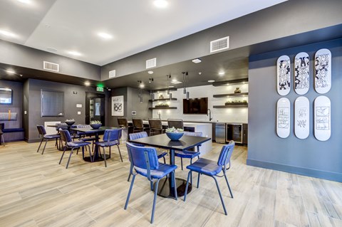 a dining room with blue chairs and tables and a kitchen