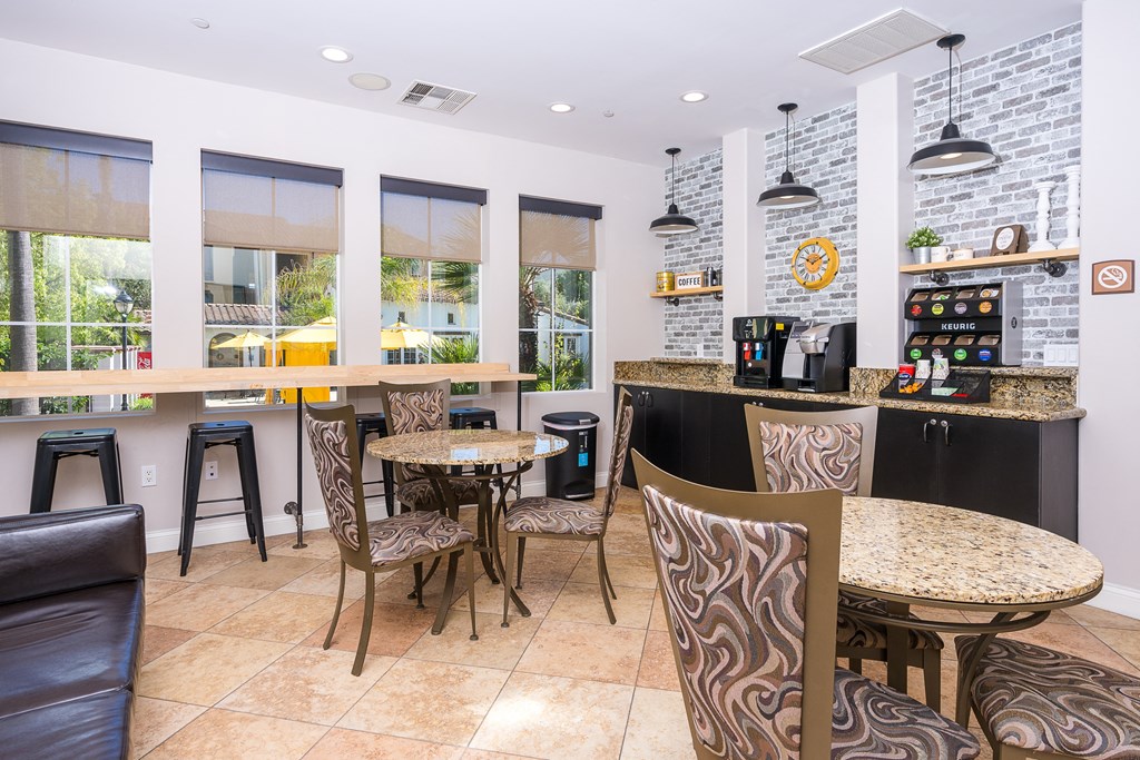 a seating area with tables and chairs in front of a counter with a coffee machine and a