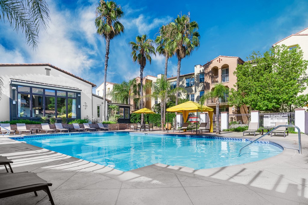 swimming pool, with seating area with umbrellas and club house.