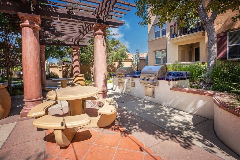 a patio with a barbecue grill and a table and chairs