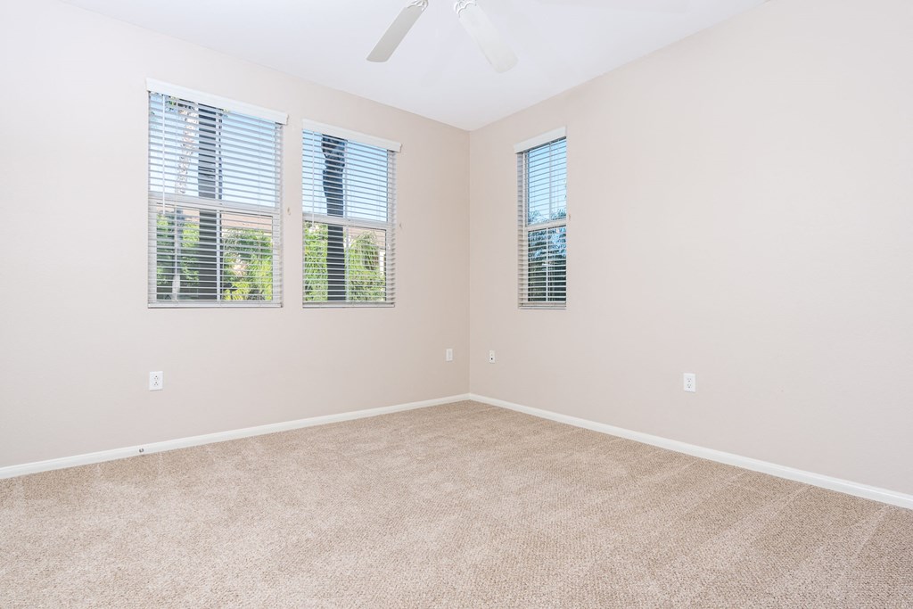 a bedroom with a ceiling fan and three windows
