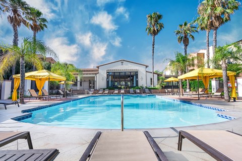 a swimming pool with yellow umbrellas and a white building in the background