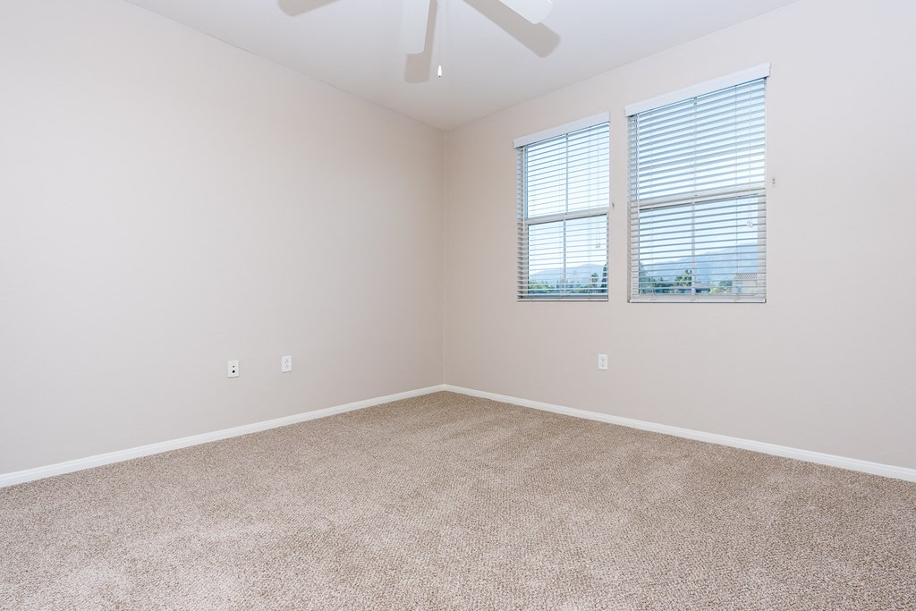 a bedroom with two windows and a ceiling fan