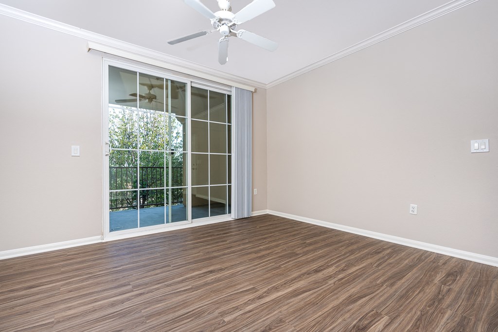 an empty living room with a sliding glass door and a ceiling fan