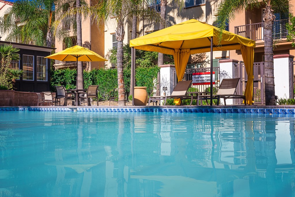 a swimming pool with a blue water and yellow umbrellas