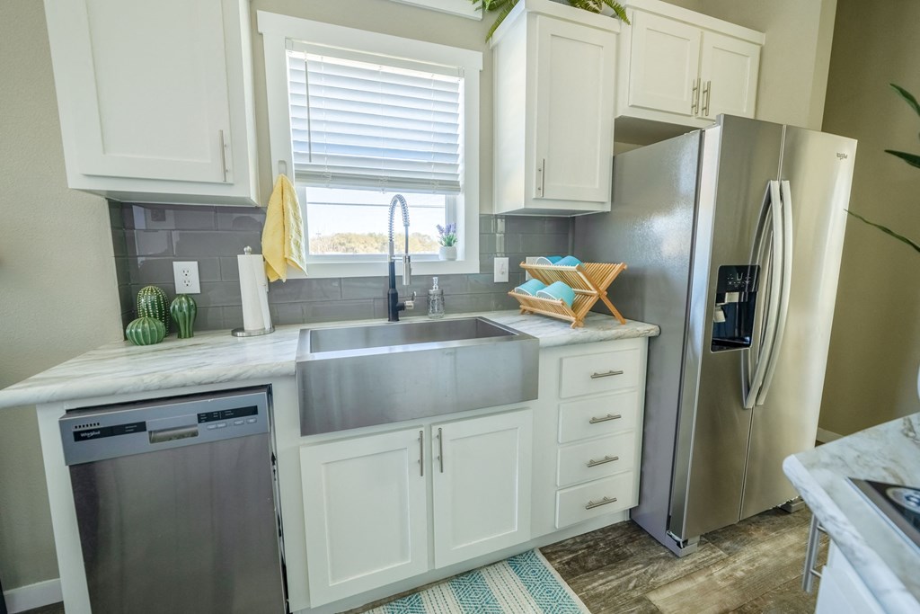 New Apartments In South Austin - Casata Austin - Kitchen With Marbled Countertops, White Cabinets, Modern Stainless-Steel Appliances, And A Window.