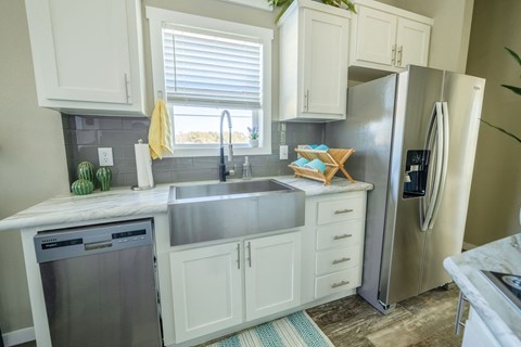 New Apartments In South Austin - Casata Austin - Kitchen With Marbled Countertops, White Cabinets, Modern Stainless-Steel Appliances, And A Window.
