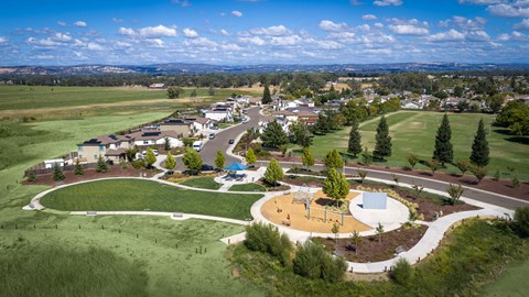 A park with a playground and a large open field.