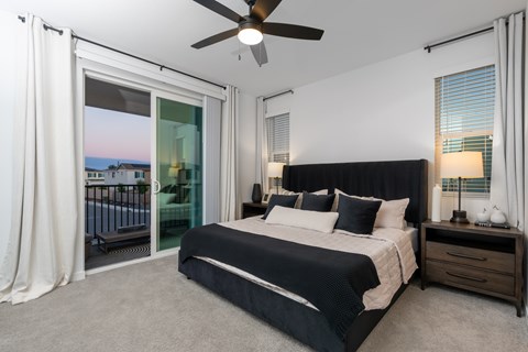3-Bedroom Homes for Rent in Lincoln, CA - Cyrene at Meadowlands - Bedroom With Upholstered Bed, Nightstands, Lamps, Windows, Carpet Flooring, and Sliding Glass Doors.