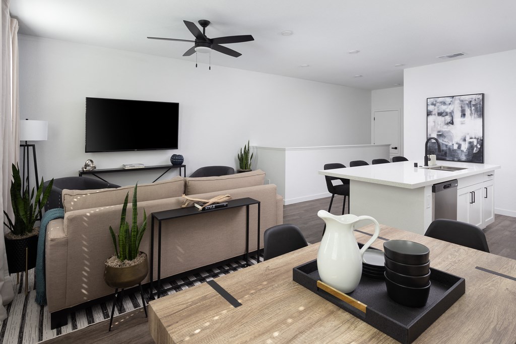 a living room and kitchen with white walls and a large tv on the wall